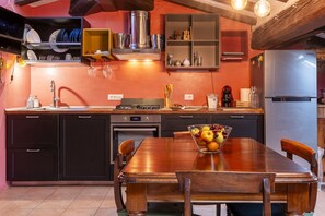A kitchen with a wooden table, a fruit bowl, and a stainless steel refrigerator. - GuestHost - Stylish Apartment in the Heart of Livorno (Livorno)