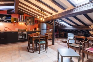 A kitchen with wooden beams, a dining table, chairs, and a refrigerator. - GuestHost - Stylish Apartment in the Heart of Livorno (Livorno)