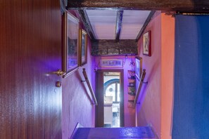 A narrow hallway with wooden walls and a ceiling with exposed beams. There are framed pictures on the walls and a staircase leading to another room. - GuestHost - Stylish Apartment in the Heart of Livorno (Livorno)