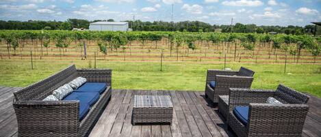 A wooden deck with wicker furniture and a vineyard view.