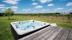 Un jacuzzi en una terraza de madera con un viñedo al fondo.