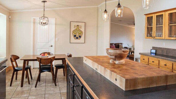 Una cocina con isla central, armarios de madera e iluminación colgante.