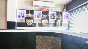 A bar area with shelves of liquor bottles, a sign for SMIRNOFF, and a patterned wall.