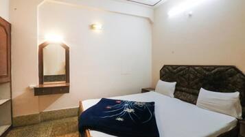 Habitación de hotel con cama, mesita de noche, espejo y lámpara de pared.