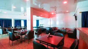A restaurant with multiple tables and booths, ceiling fans, and a view of the outside.