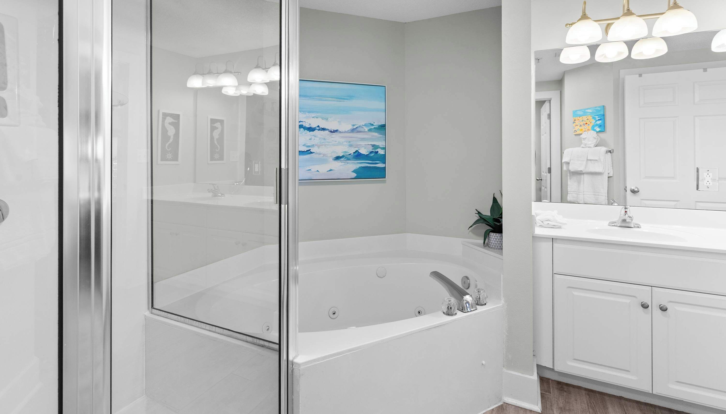 Un bagno moderno con cabina doccia in vetro, una vasca da bagno ampia e un mobile lavabo bianco con specchio.
