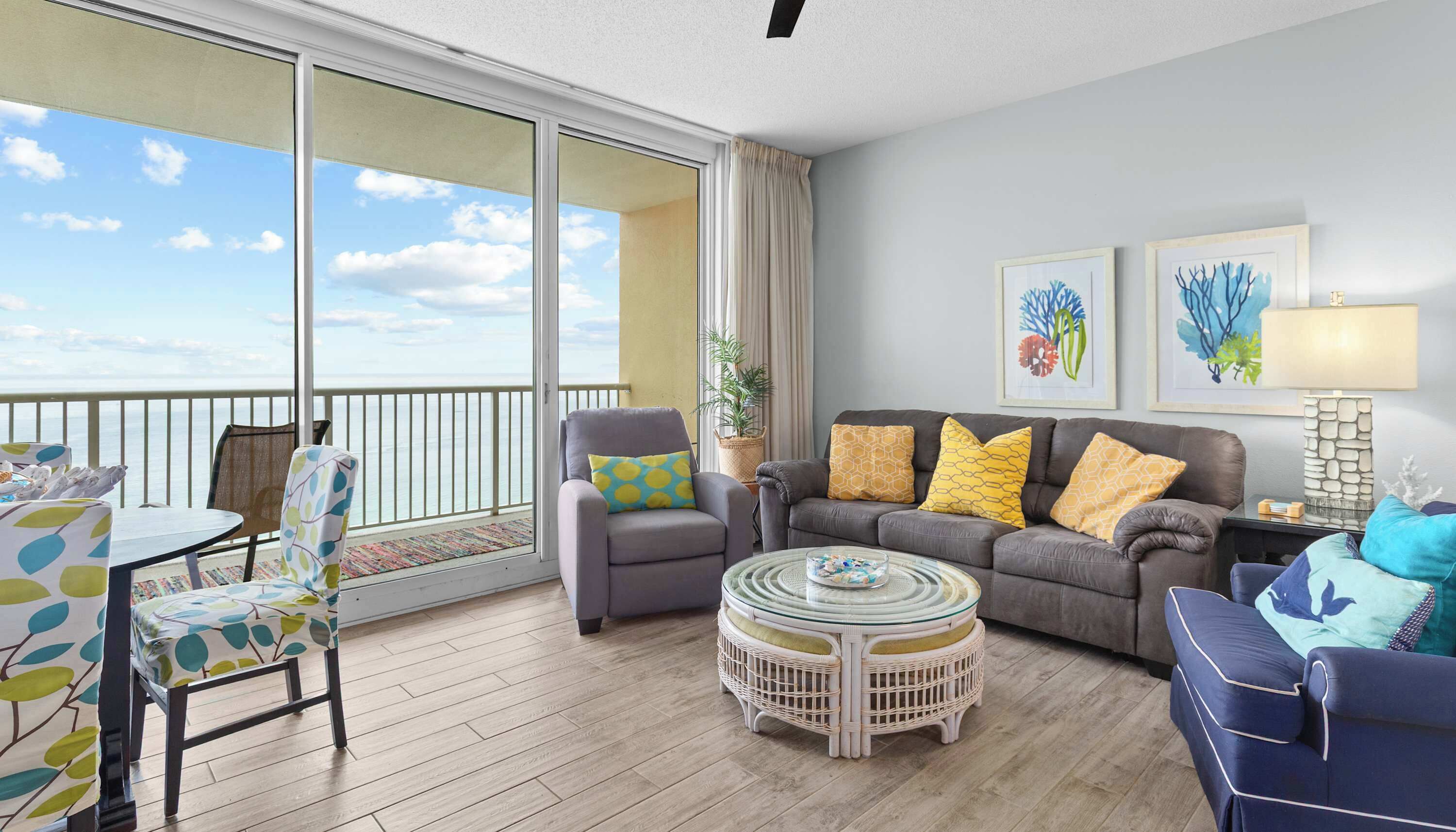 A balcony with a view of the sea, a seating area with a sofa and chairs, and a dining table.
