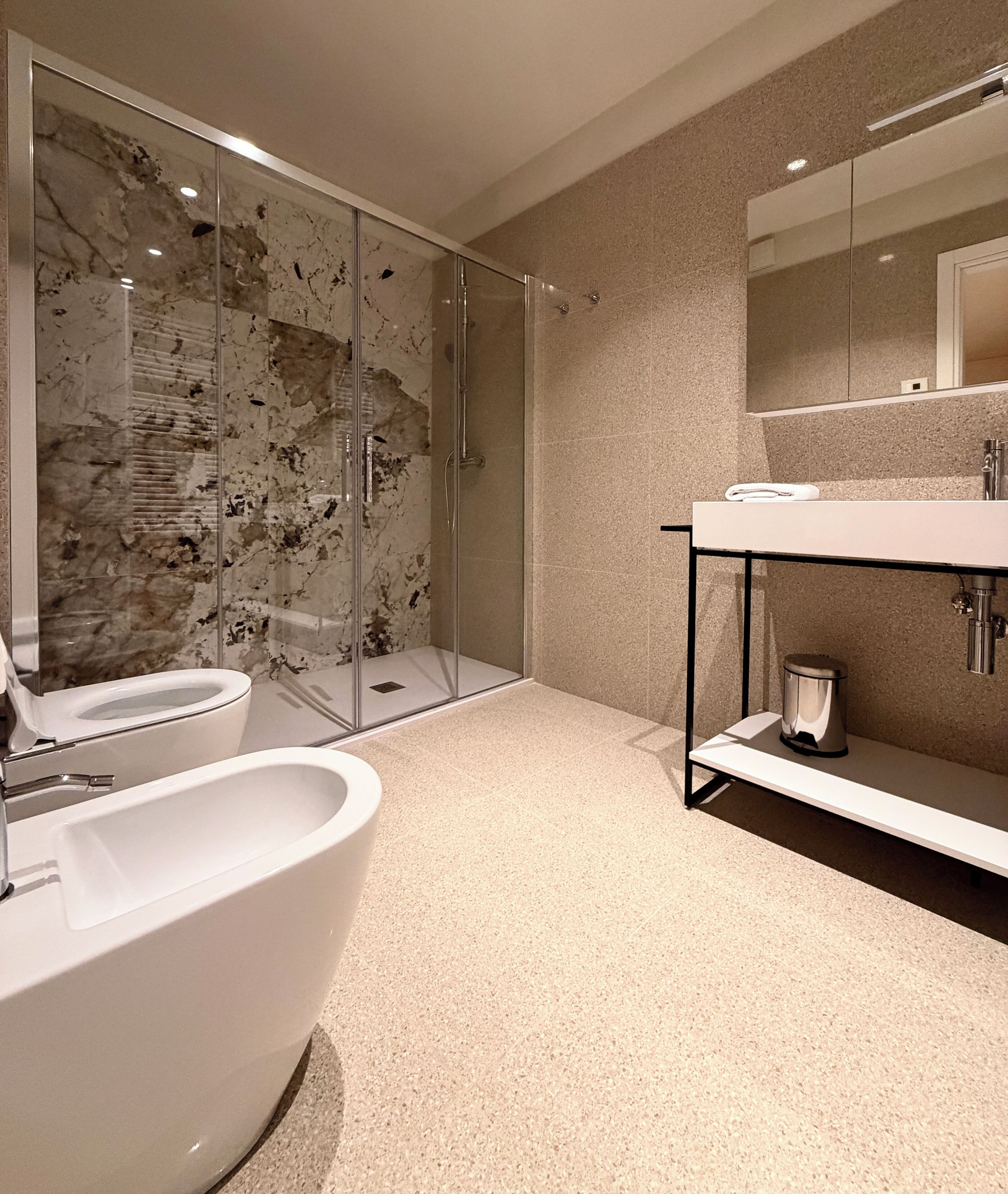 A modern bathroom with a glass-enclosed shower, a freestanding bathtub, and a vanity with a mirror.