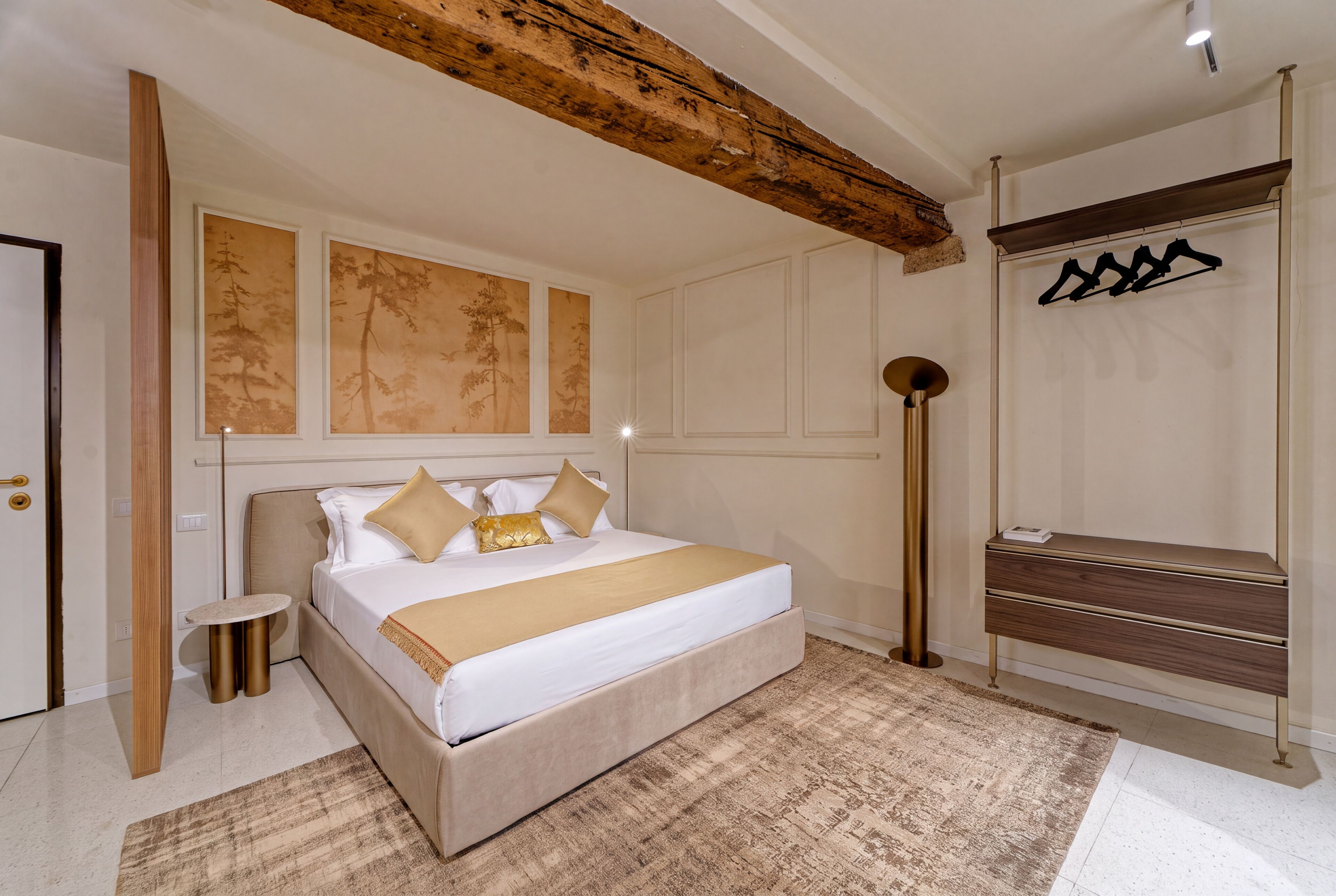 A bedroom with a bed, a bedside table, a floor lamp, and a wardrobe.