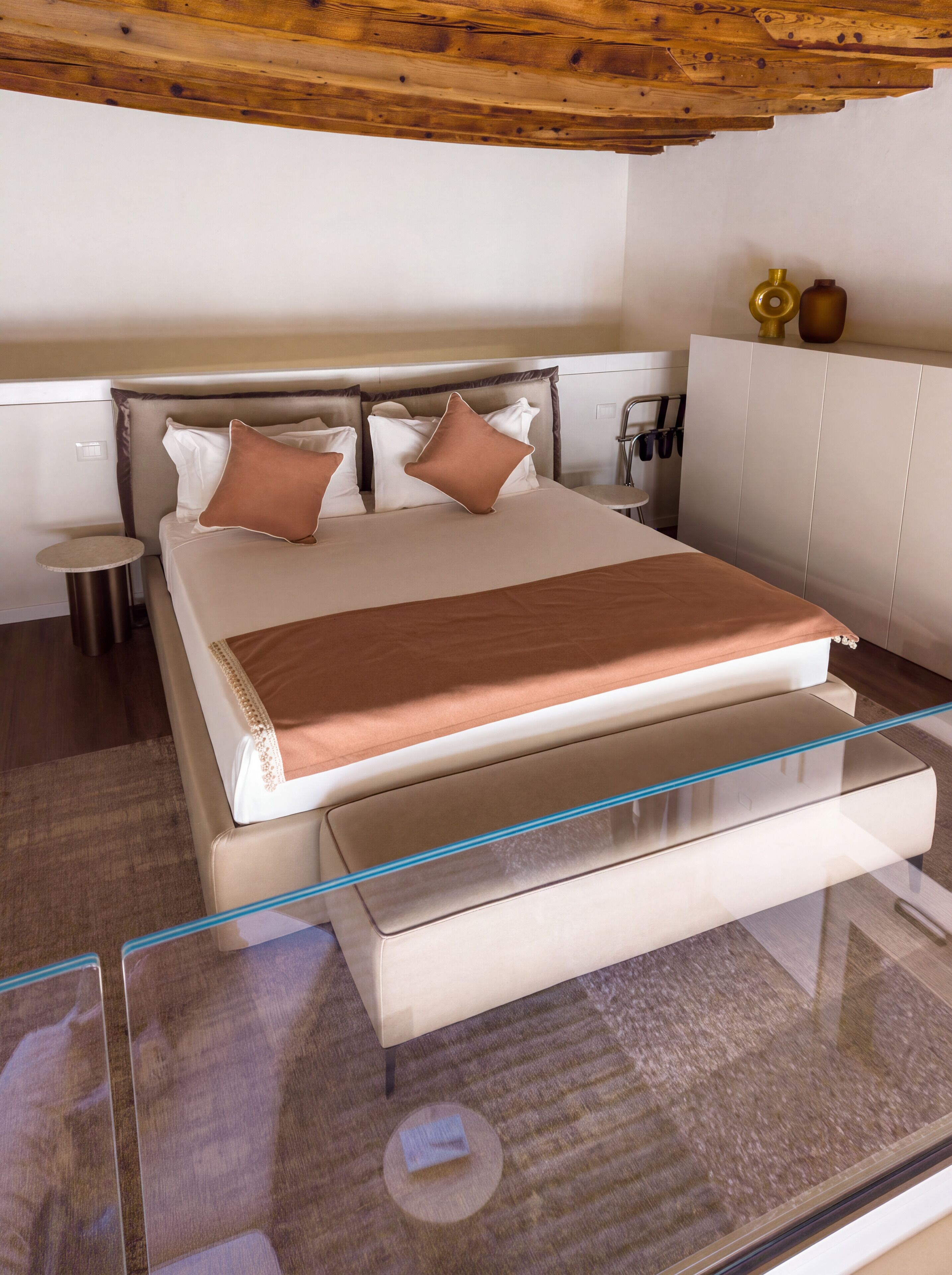A modern hotel room with a bed, bedside table, and a glass-enclosed desk.