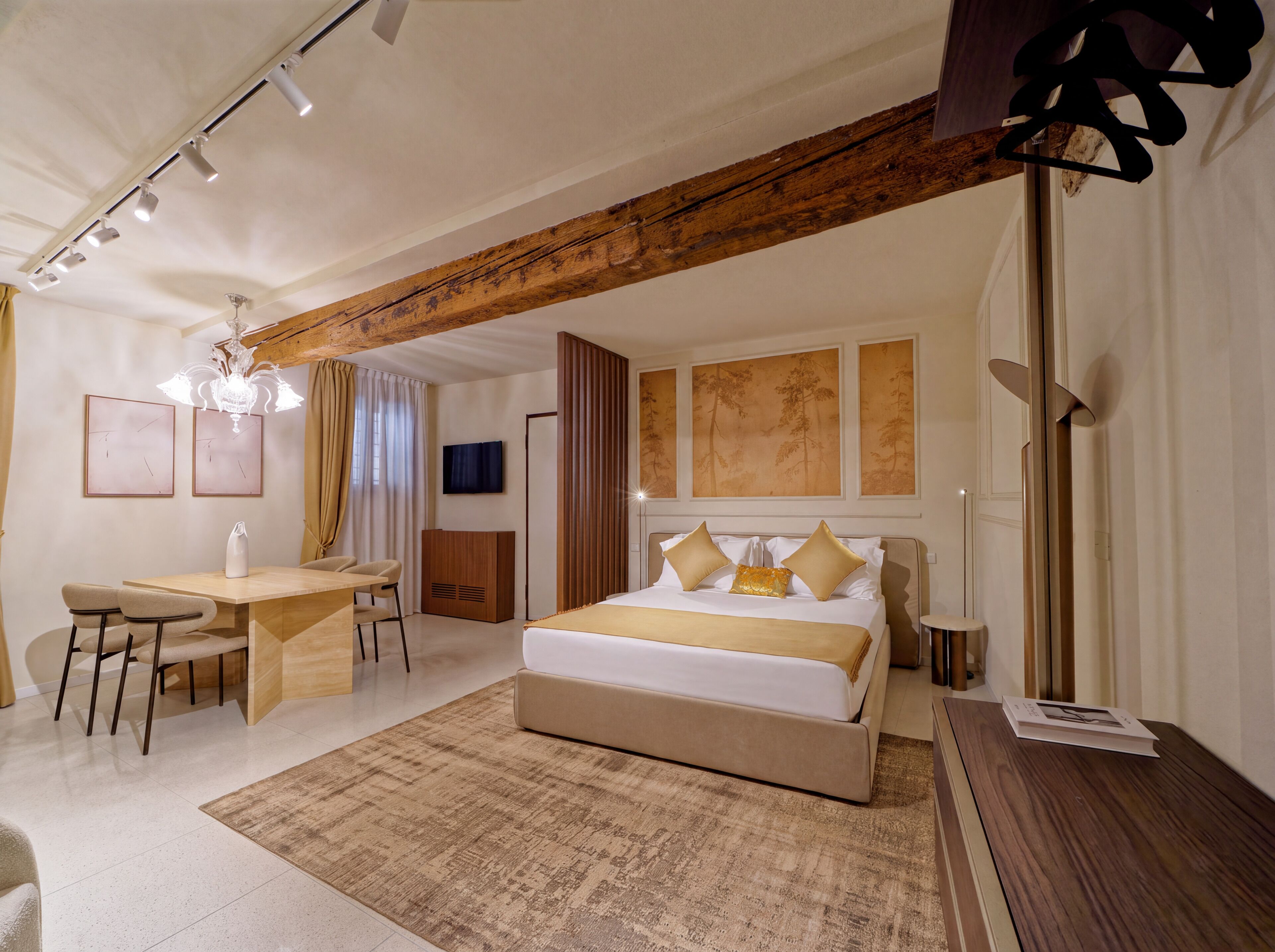Une chambre d’hôtel moderne, dotée d’un grand lit, d’un bureau avec des chaises, d’une télévision et d’œuvres d’art accrochées aux murs.