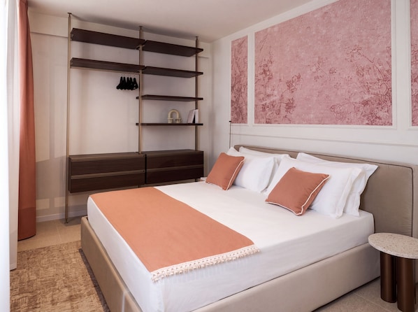 A bedroom with a bed, a nightstand, a dresser, a shelf unit, and a round table.