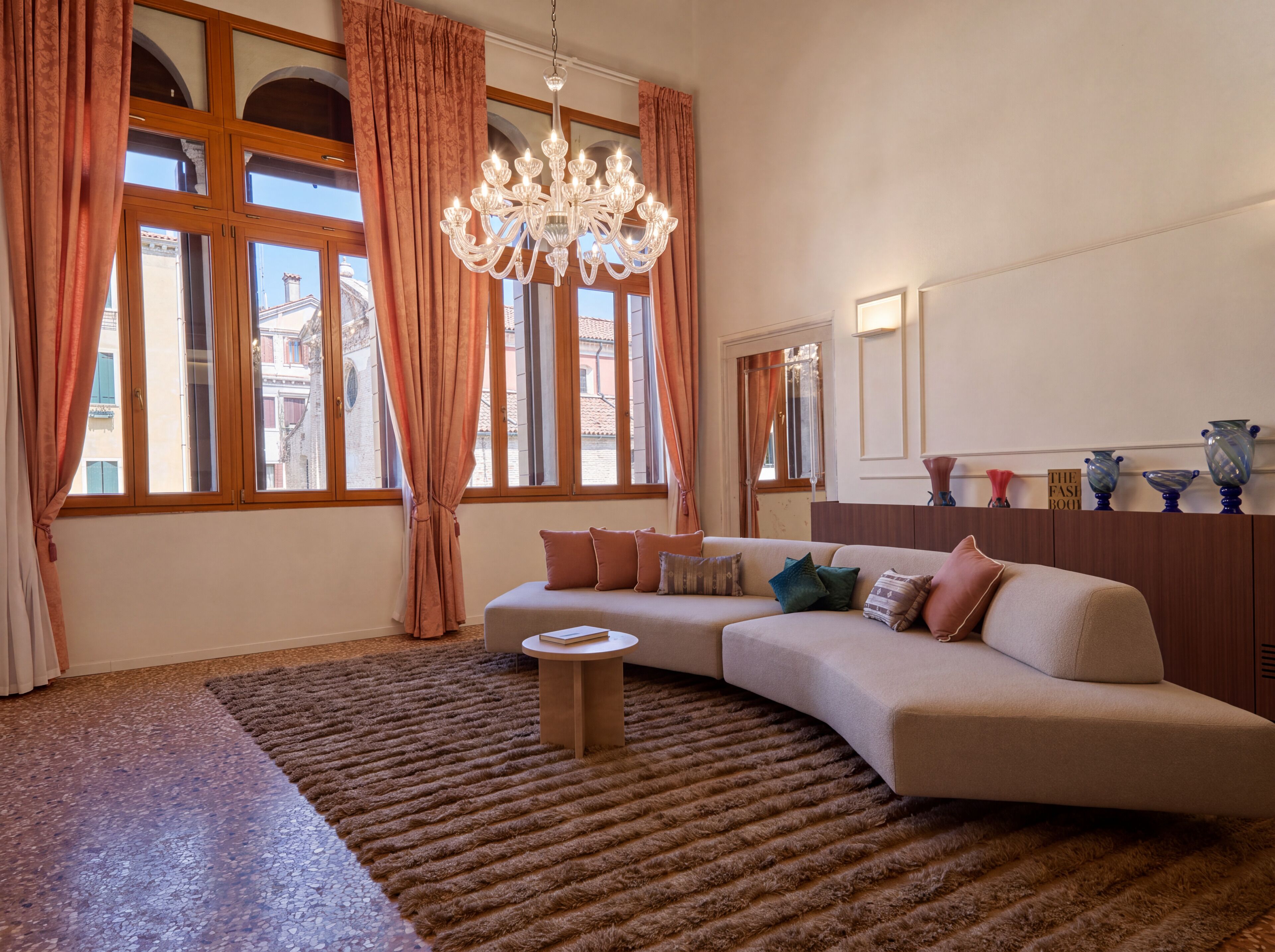 A living room with a large window, a chandelier, a sofa, and decorative vases.