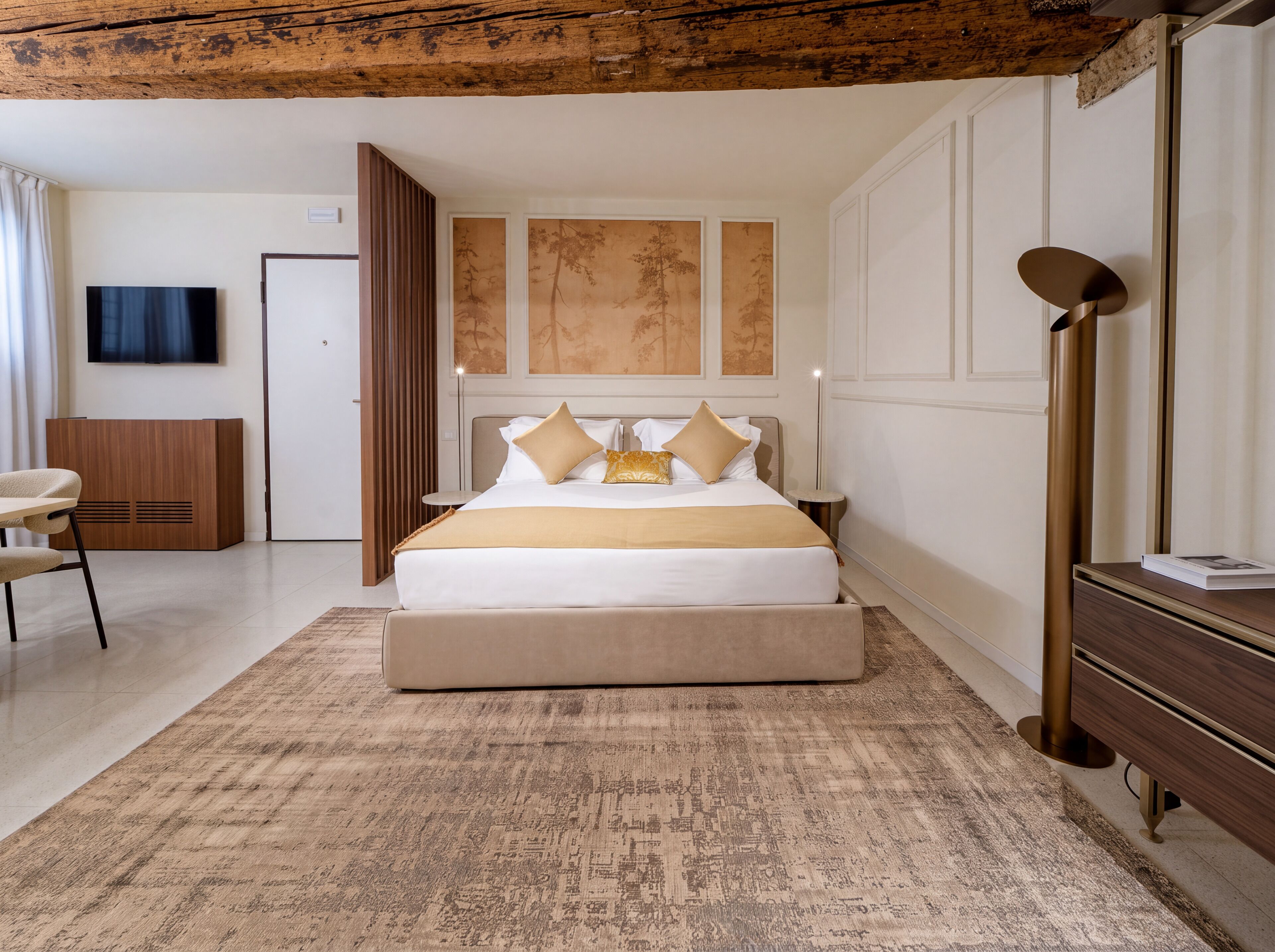 Habitación de hotel moderna con una cama grande, un televisor de pantalla plana, un armario de madera y un escritorio con una silla.
