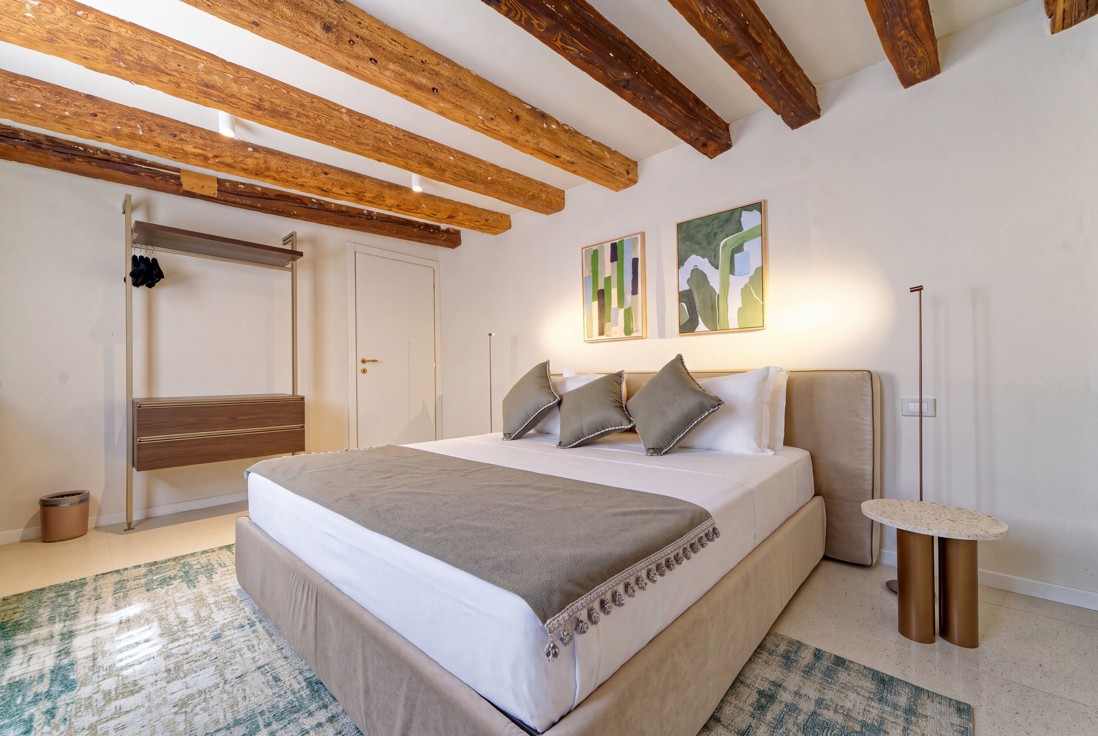 A bedroom with a bed, bedside table, and a hanging coat rack.