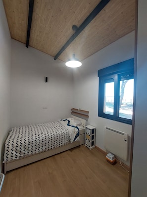Ein Schlafzimmer mit einem Bett, einem Fenster, einer Heizung und einem Deckenventilator.