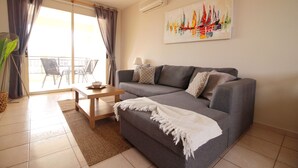 Un salon avec un canapé, une table basse, une lampe et un tableau au mur.