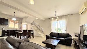 Un salon moderne comprenant un canapé, une table basse, un téléviseur et un escalier menant à la cuisine.