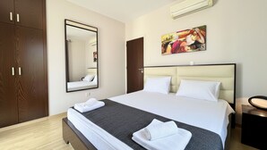 Une chambre d’hôtel avec un grand lit, une armoire, un miroir et un tableau au mur.