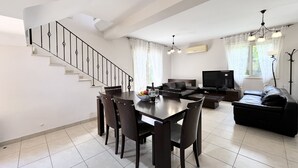 Un salon moderne comprenant un coin repas, un escalier, un téléviseur à écran plat et un canapé.