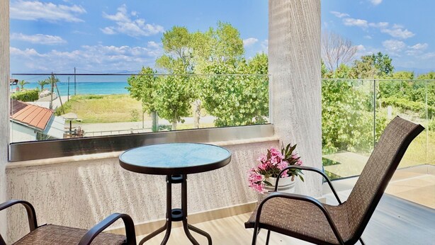 A balcony with a table and chairs, overlooking a beach and greenery. - Villa La Bella Sofia with private pool (Roda)