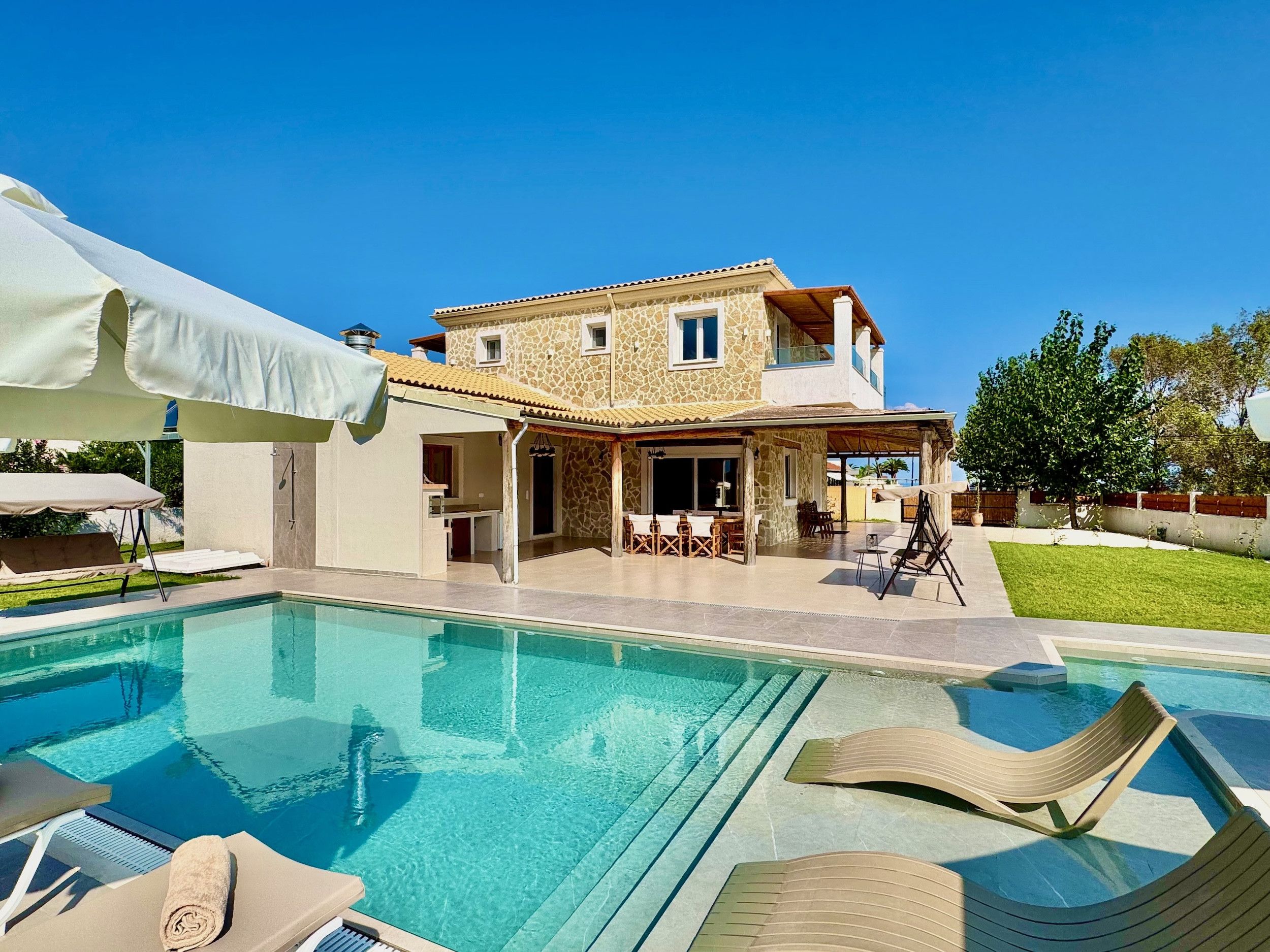 Uma casa de dois andares com piscina, área de estar externa e varanda coberta.
