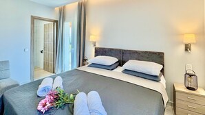 A hotel room with a bed, bedside lamps, a nightstand, and a door leading to a balcony. - Villa La Bella Sofia with private pool (Roda)
