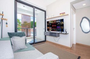 A modern hotel room with a large sliding glass door to a balcony, a mounted TV, and a shelf with various items. - Corporate Stays Spirit Mariscal (Asunción)
