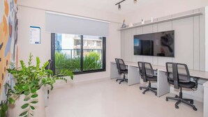 Ein moderner Büroarbeitsplatz mit großem Fenster, Flachbildfernseher und mehreren Bürostühlen.