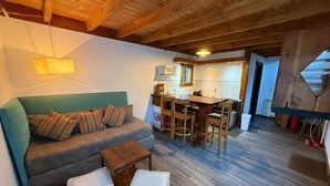 A cozy living area with a sofa, ottomans, a dining table, and chairs. - Inlandsis Aparts (El Chalten)