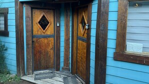 A wooden front door with a diamond-shaped window and a welcome mat. - Inlandsis Aparts (El Chalten)