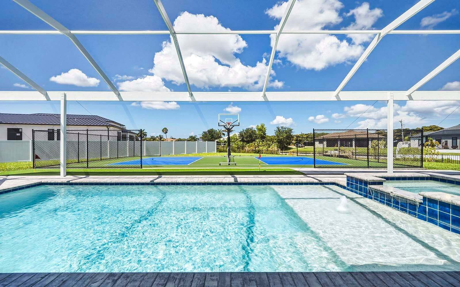 Une piscine avec, en arrière-plan, un terrain de basket-ball et un court de tennis.