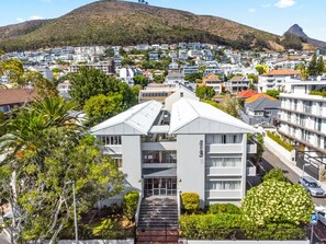 A modern building with a flat roof, multiple floors, and a prominent entrance. - Modern Green Point Studio Walk to Promenade (Cape Town)