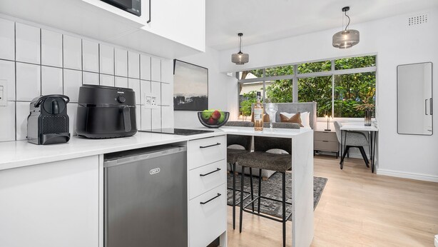 Una cocina moderna con armarios blancos, cafetera y lavavajillas.