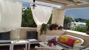 An outdoor patio with white furniture, a ceiling fan, and potted plants. - Villa Marica (Ostuni)