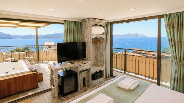 A balcony with a view of the sea, a TV, a fireplace, a sofa, and a bathtub. - Payam Agora Hotel Room Only, Shared Terrace & Kitchen (Kas)