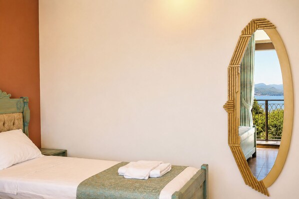 A bedroom with a bed, a large mirror, and a view of a balcony with a railing.