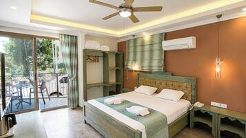A bedroom with a bed, a ceiling fan, a bedside table, a nightstand, and a view of the outdoors.