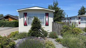 A mobile home with a small front yard, a metal sculpture, and a neighboring house. - Waterview Chalet Near Marina Beach (Sint-Annaland)