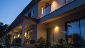 A modern two-story house with a covered porch, large windows, and a well-lit entrance. - Quinta Tapada do Vale - Wine Estate Retreat (Carregal do Sal)