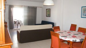 Una sala de estar con sofá, mesa de comedor, sillas y una lámpara de techo.