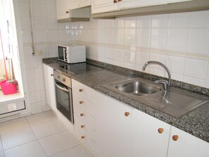 A kitchen with white cabinets, a stainless steel sink, a microwave, and a red bucket. - Spacious apartment with pool and parking - 6 guests (Gandia)