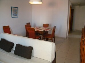 Un coin repas avec une table et des chaises, un canapé avec des coussins et un tableau encadré au mur.