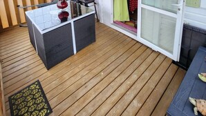 A covered outdoor area with a table and chairs, a sliding glass door, and a wooden deck. - Practical mobile home, pets welcome - 4 guests (Biville-sur-Mer)