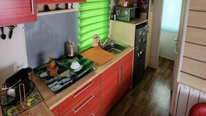 A compact kitchen with red cabinets, a green window blind, and a microwave. - Practical mobile home, pets welcome - 4 guests (Biville-sur-Mer)