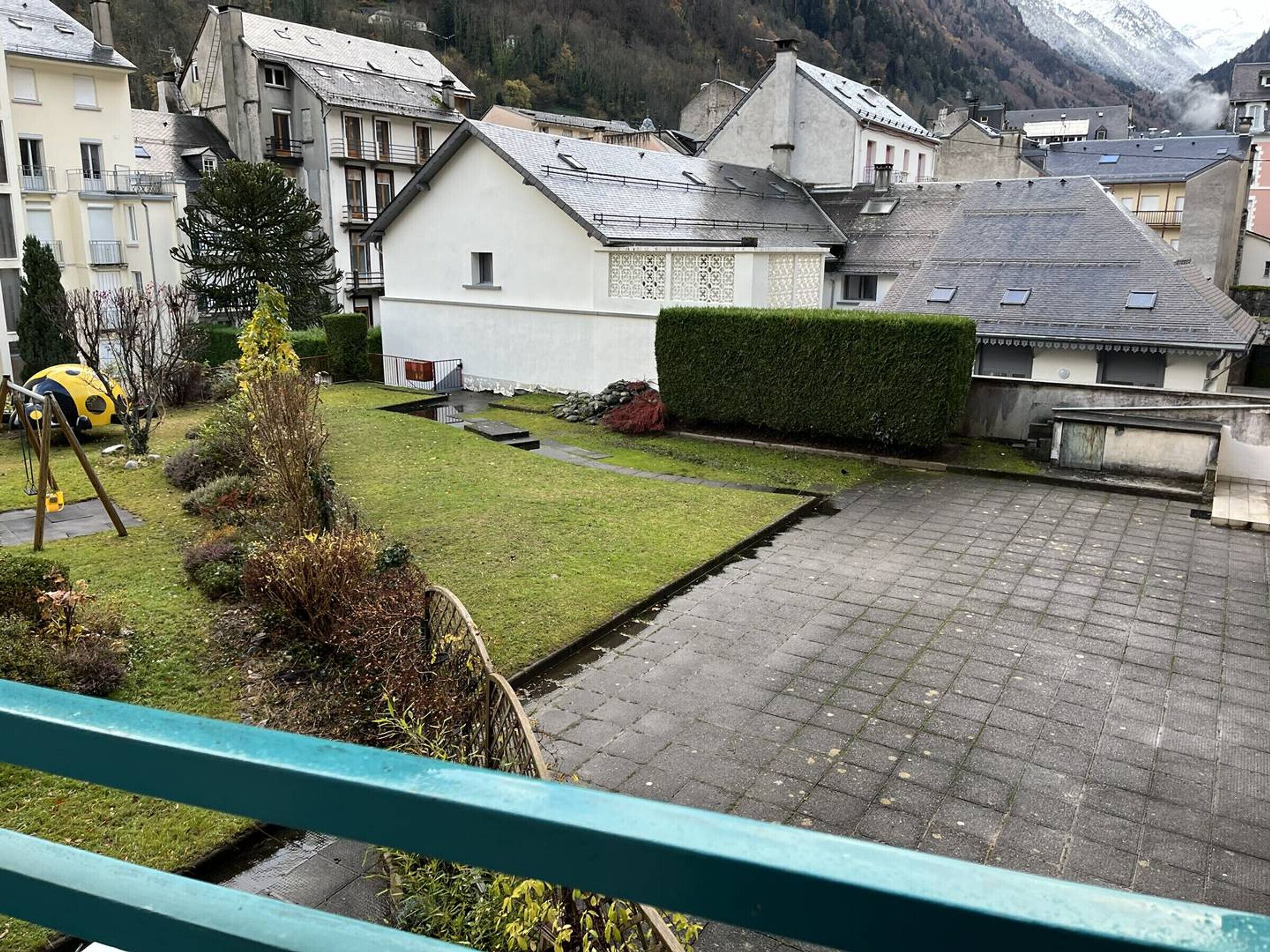 Un quartier résidentiel avec des maisons, une cour pavée et une chaîne de montagnes en arrière-plan.