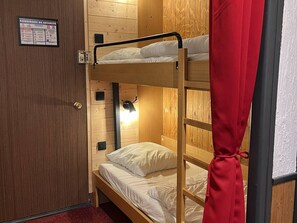 A bunk bed room with wooden walls, a security sign, a light fixture, and a red curtain. - Charming studio, terrace mountain view - 4 guests (Cauterets)