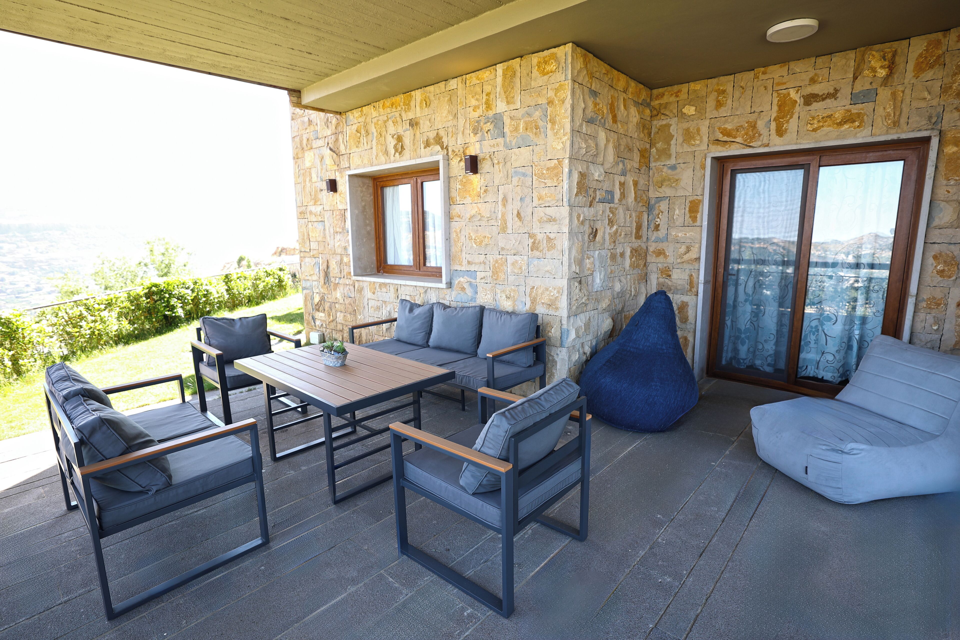 Une terrasse extérieure avec des murs en pierre, une table en bois et des sièges comprenant un canapé et des fauteuils.