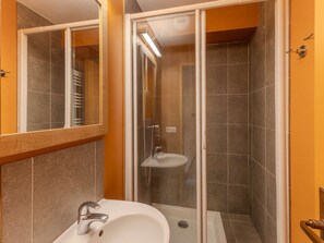 Un bagno con doccia, lavandino e specchio.
