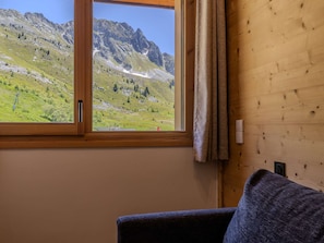 A room with a window offering a mountain view, a wooden wall, and a dark-colored chair. - Refined duplex apartment - 2 guests (Belle Plagne)